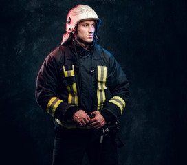 Fototapeta premium Studio portrait of firefighter dressed in uniform and safety helmet looking sideways with a confident look