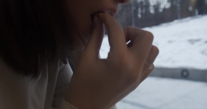 Girl dips a cookie in coffee inside a caffee on a winter day CLOSEUP
