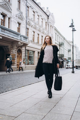 Young blondie business woman rushing to a business meeting. Walking along old historic european town 