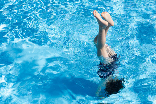 Little girl doing handstand in swimming pool