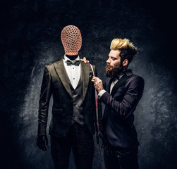 An elegantly dressed fashion designer with expressive style working with custom made men's suit in...