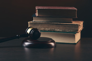 Law concept - Open law book with a wooden judges gavel on table in a courtroom