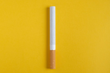 Cigarette in the center on a yellow background. Top view.