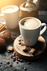 Black fried coffee beans in cafe with cookie and cake on dark textured background