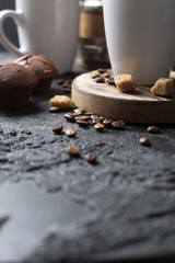 Black fried coffee beans in cafe with cookie and cake on dark textured background