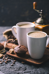 Black fried coffee beans in cafe with cookie and cake on dark textured background