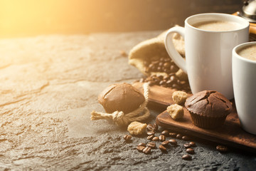 Black fried coffee beans in cafe with cookie and cake on dark textured background