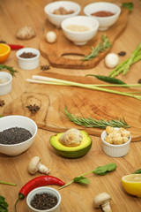  Wooden cutting board surrounded with a variety of herbs, spices, fruits and vegetables