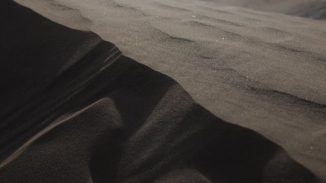 Sand blows over the top of sand dune in slow motion. Shot in UAE.