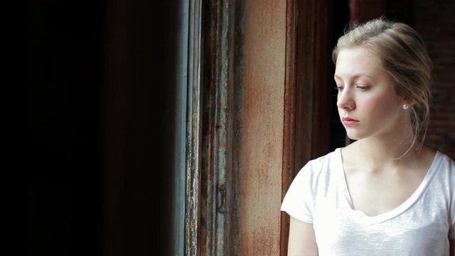 Camera Pans Right To Reveal Sad Young Woman Looking Out Window