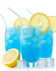 Blue lagoon cocktails with ice cubes, lemon and straw on white