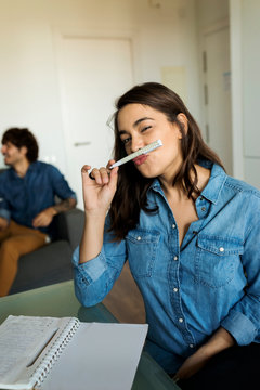 Portrait of woman taking notes at dining table with friend in background