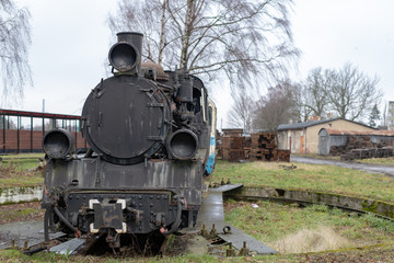 Fototapeta na wymiar Old rusty locomotive of the narrow gauge railway. Place of stationing of old steam locomotives.