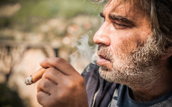Portrait of bearded caucasian man smoking a cigar