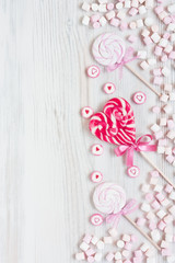 Assorted colored lollipop candy and marshmallow on white background for greeting card. Top view