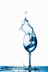 Wineglass With Water Splash and Drops In Motion Against Pure White Background.
