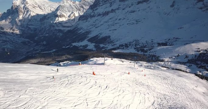 Side shot of skiers traveling down Swiss alps ski field covered in snow, Switzerland 4k