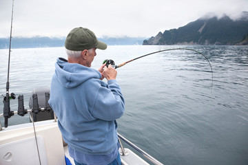 Senior fisherman reeling in a fish near Seward, Alaska