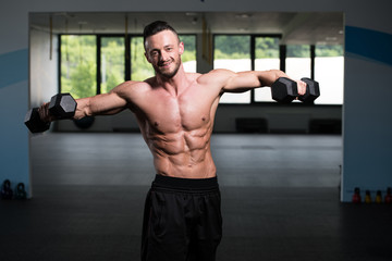 Bodybuilder Exercising Shoulders With Dumbbells