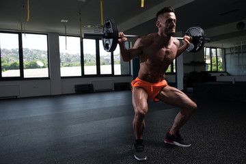 Fototapeta na wymiar Man Exercising Legs With Barbell In The Gym