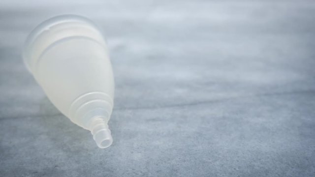Woman's menstrual cup falls and bounces off a marble countertop in slow motion. The silicone feminine hygiene product is an eco-friendly, sustainable, zero waste alternative to pads or tampons.