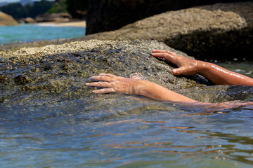 woman's hand out of the water trying to grab the coastal stone and escape from the sea. Close-up. Copy space
