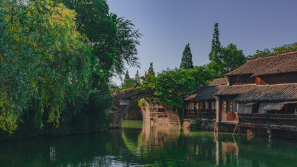 Fototapeta na wymiar Traditional Chinese houses and bridge by water under blue sky, in the old town of Wuzhen, China