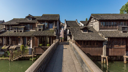 Traditional Chinese houses and bridge by water under blue sky, in the old town of Wuzhen, China