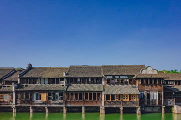 Naklejka premium Traditional Chinese houses by water under blue sky, in the old town of Wuzhen, China