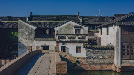 Fototapeta premium Traditional Chinese houses and bridge by water under blue sky, in the old town of Wuzhen, China