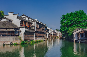 Fototapeta na wymiar Traditional Chinese houses and trees by water, in the old town of Wuzhen, China