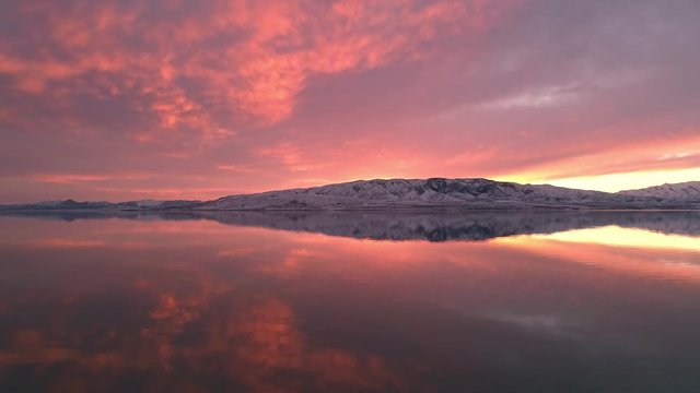 View of colorful pink sunset reflecting in Utah Lake viewed from drone over the water.