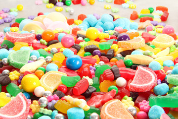 Fototapeta na wymiar Assorted variety of sweet sugar candies includes lollipops, gummy bears, gum balls and sugar fruit slices.