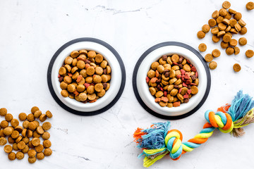Animal food in bowl on white stone background top view