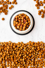 Dry dog food in bowl on white stone backgorund top view space for text