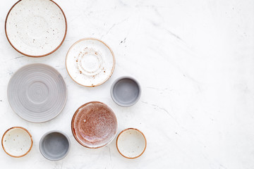 Kitchen concept. Crockery kit. Empty ceramic plates and mugs on white background top view copy space
