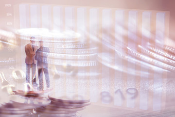 Double exposure of coins of Two Business man and clock,saving and finance concepts. Miniature people Stand in front of a coin,soft focus and blurred style.