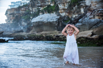 little girl playing with water in a beautiful beach with rocks in Australia