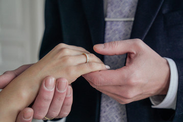 Man holding woman's hand with engagement ring, wedding day