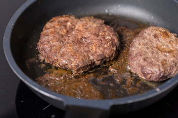 Beef burger being cooked on a black pan