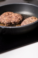 Beef burger being cooked on a black pan