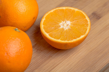 Orange fruit cut on halves on a wooden surface
