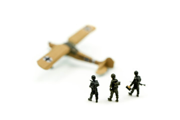 Miniature people : team soldier standing together with army tank and aircraft air combat using for Toy Soldier Day concept.