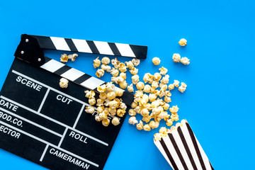 Film watching concept. Clapperboard and popcorn on blue background top view