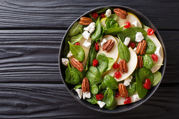 Dietary raw salad of pears, spinach, pecans, goat cheese and dried cherries close-up on a plate. horizontal top view