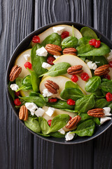 Spicy fruit salad with pears, baby spinach, pecans, feta cheese and cherries closeup on a plate. Vertical top view