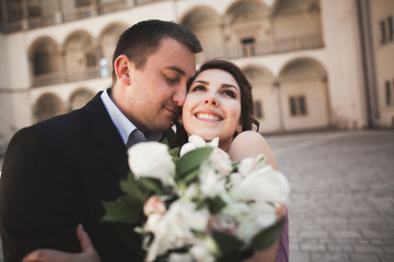 Beautiful couple, man, girl with long pink dress posing in old castle near columns. Krakow Vavel