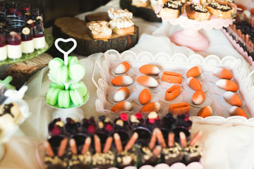 Delicious and tasty dessert table with cupcakes shots at reception closeup