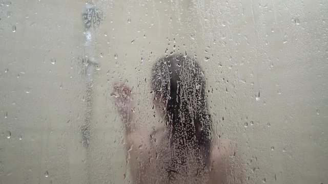 Slender girl taking shower in bathroom. Close-up.