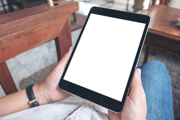 Mockup image of a woman's hands holding black tablet pc with blank white screen while sitting in cafe